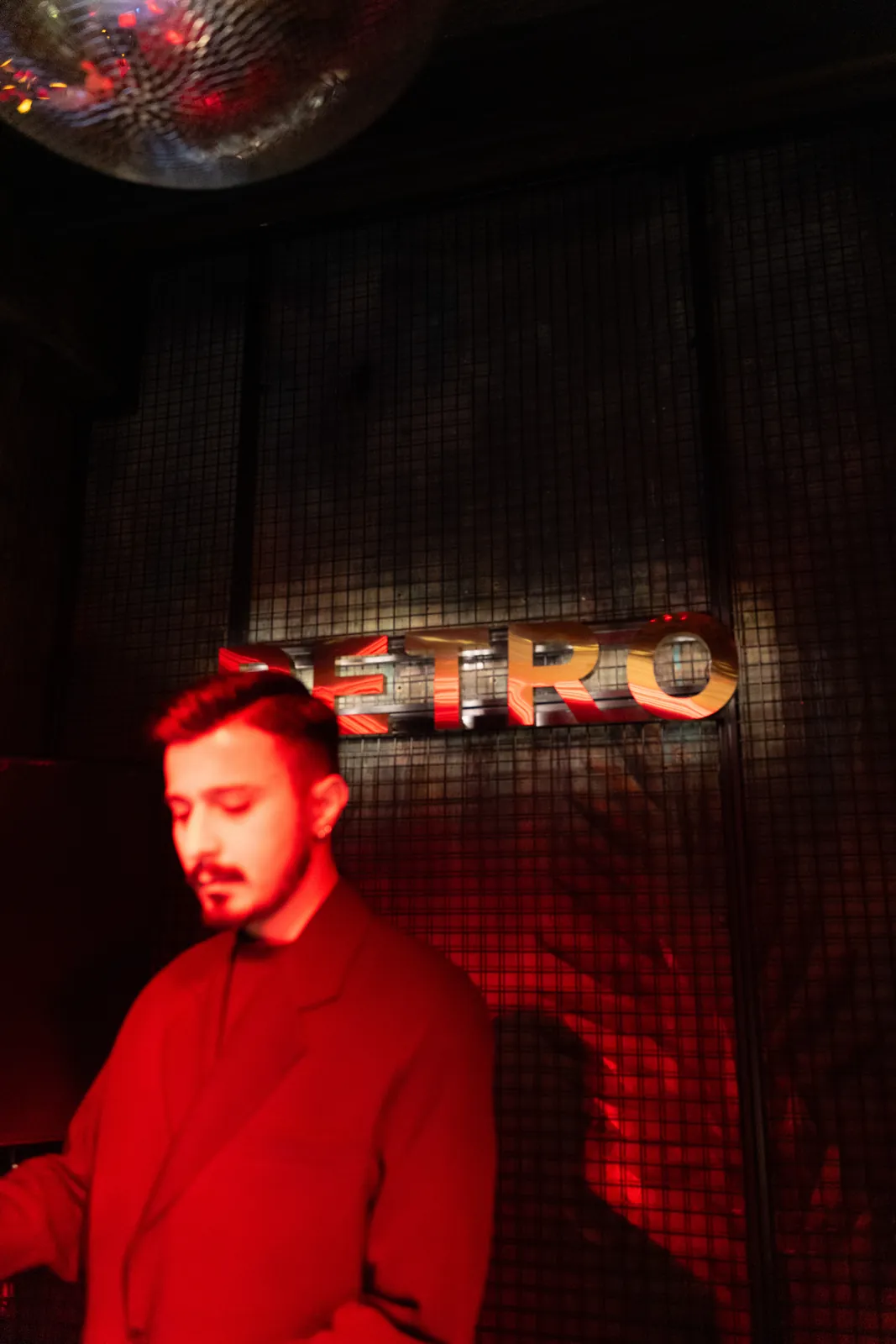 Neon PETRO tabelasının önünde kırmızılar içinde DJ